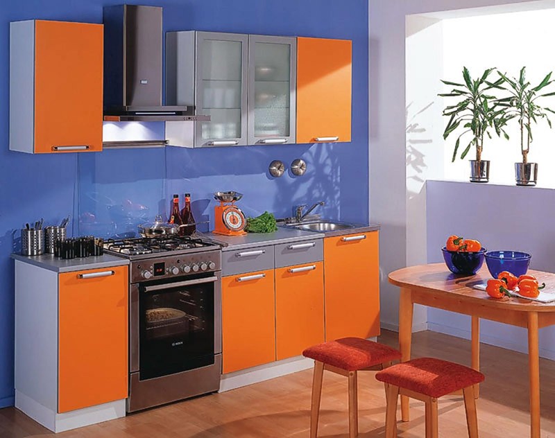 Оранжевые шкафчики на кухне на фоне синей стены