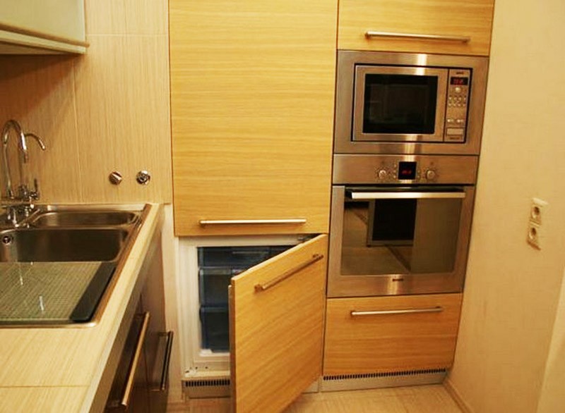 Маленький холодильник в высоком шкафу на кухне