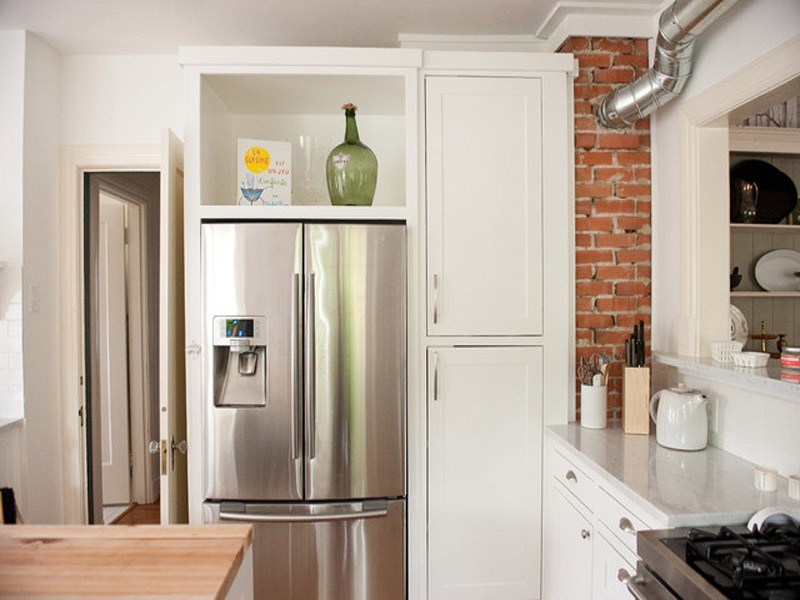 Холодильник у двери встроен в систему шкафов