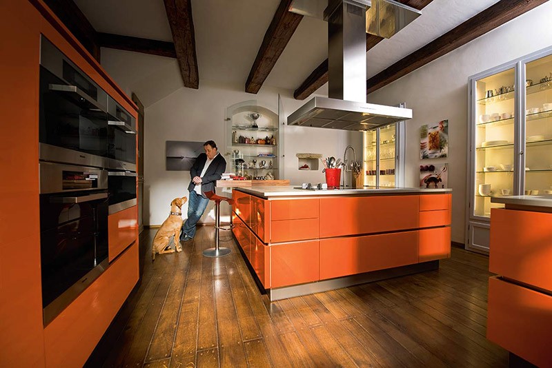 Просторная кухня-остров с белыми стенами и оранжевой мебелью