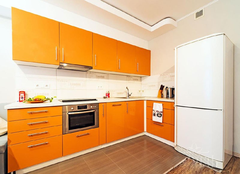 Оранжевый гарнитур на фоне белого помещения и холодильника